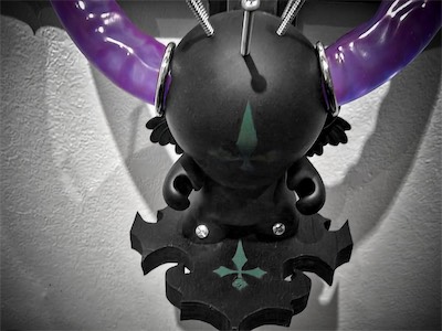 Sacred the Munny — Now we get to see a downward angle showing the platform itself with the green upside-down cross on it, and the green upside-down cross on the Munny's forehead. Also note, his feet are screwed into the platform. This is a crucifix. It's appropriate. Little wings budding out on the sides too. A bit angelic and demonic.